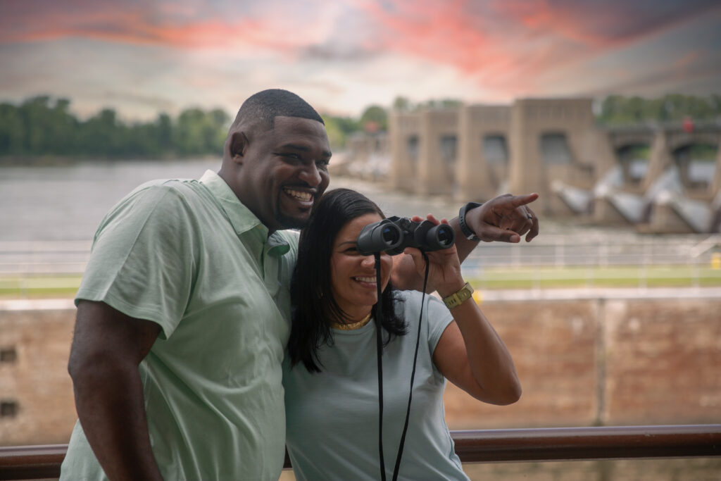 couple with binoculars/dam in background
